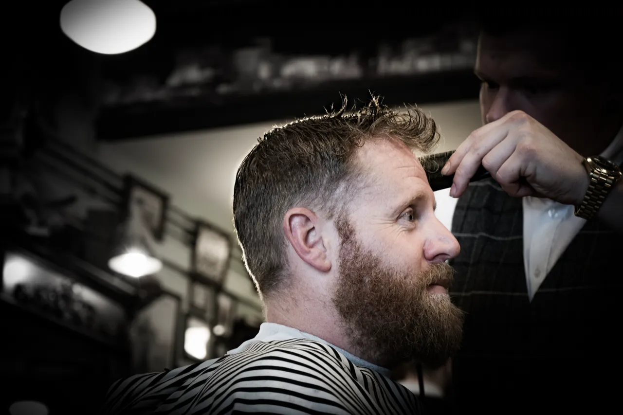 Klant in de stoel bij de barbier, tijdens het knippen
