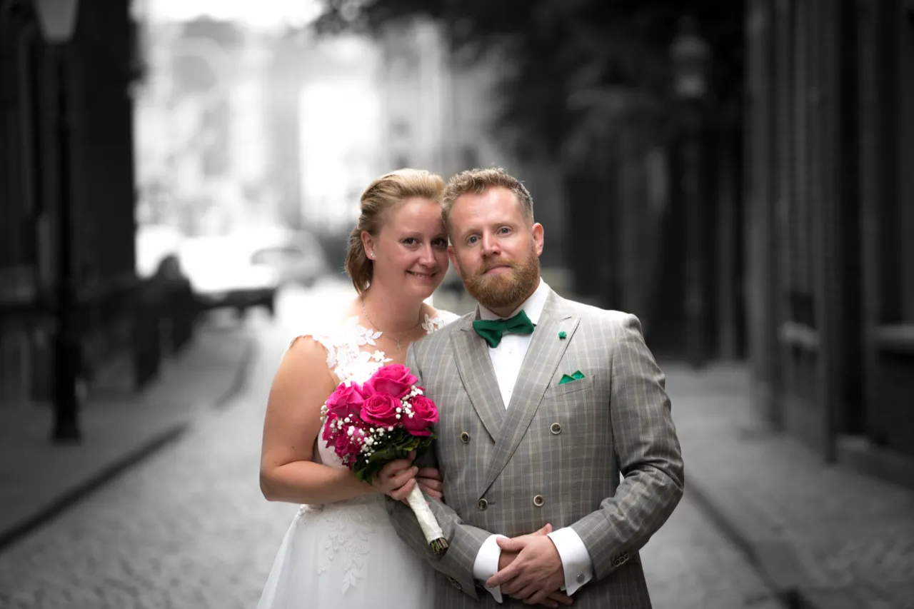 Bruidspaar in een oude straat, met het boeket in kleur