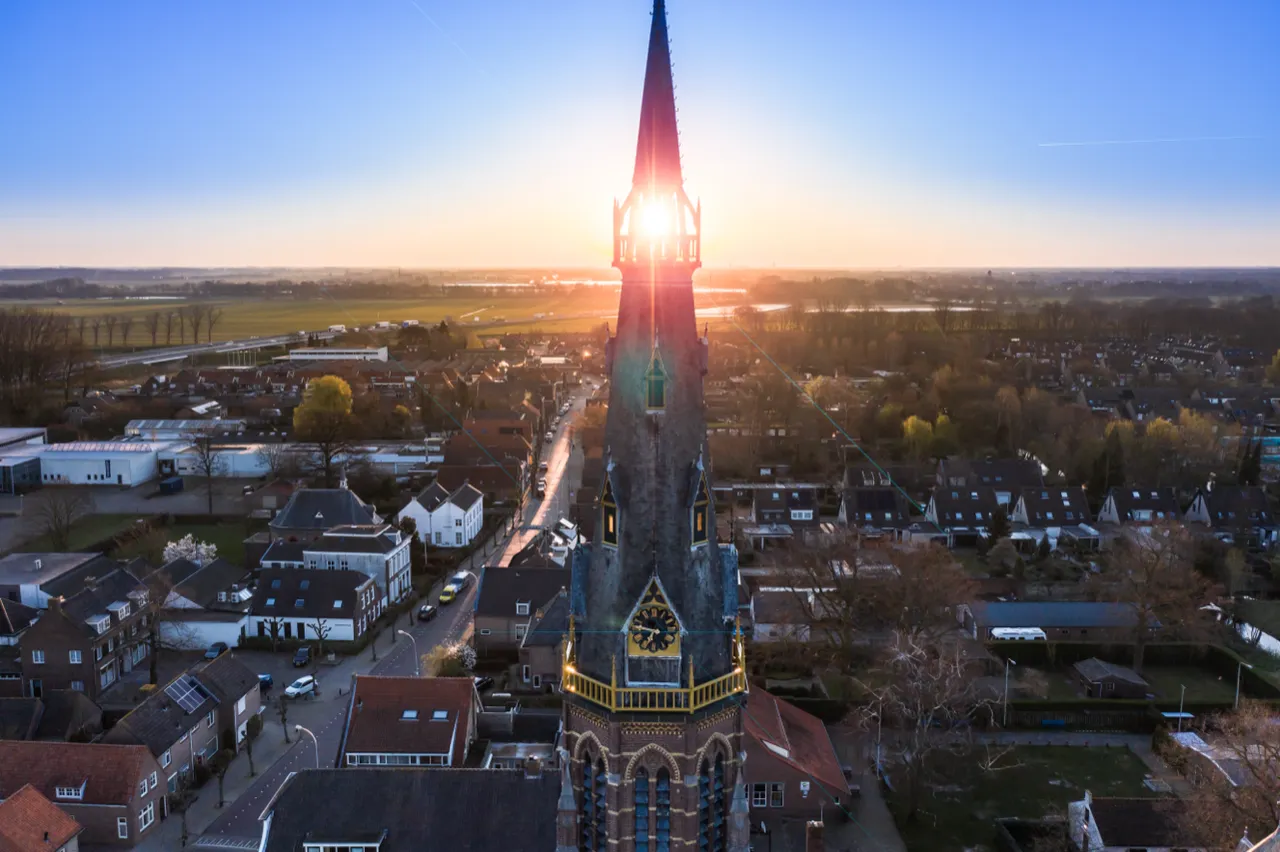 Kerktoren boven het dorp bij zonsopkomst, vanuit de lucht