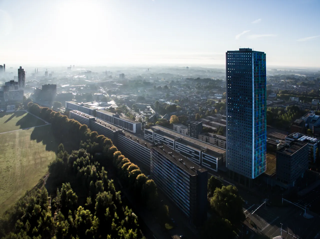 De stad in de ochtendmist, met hoogbouw boven het groen