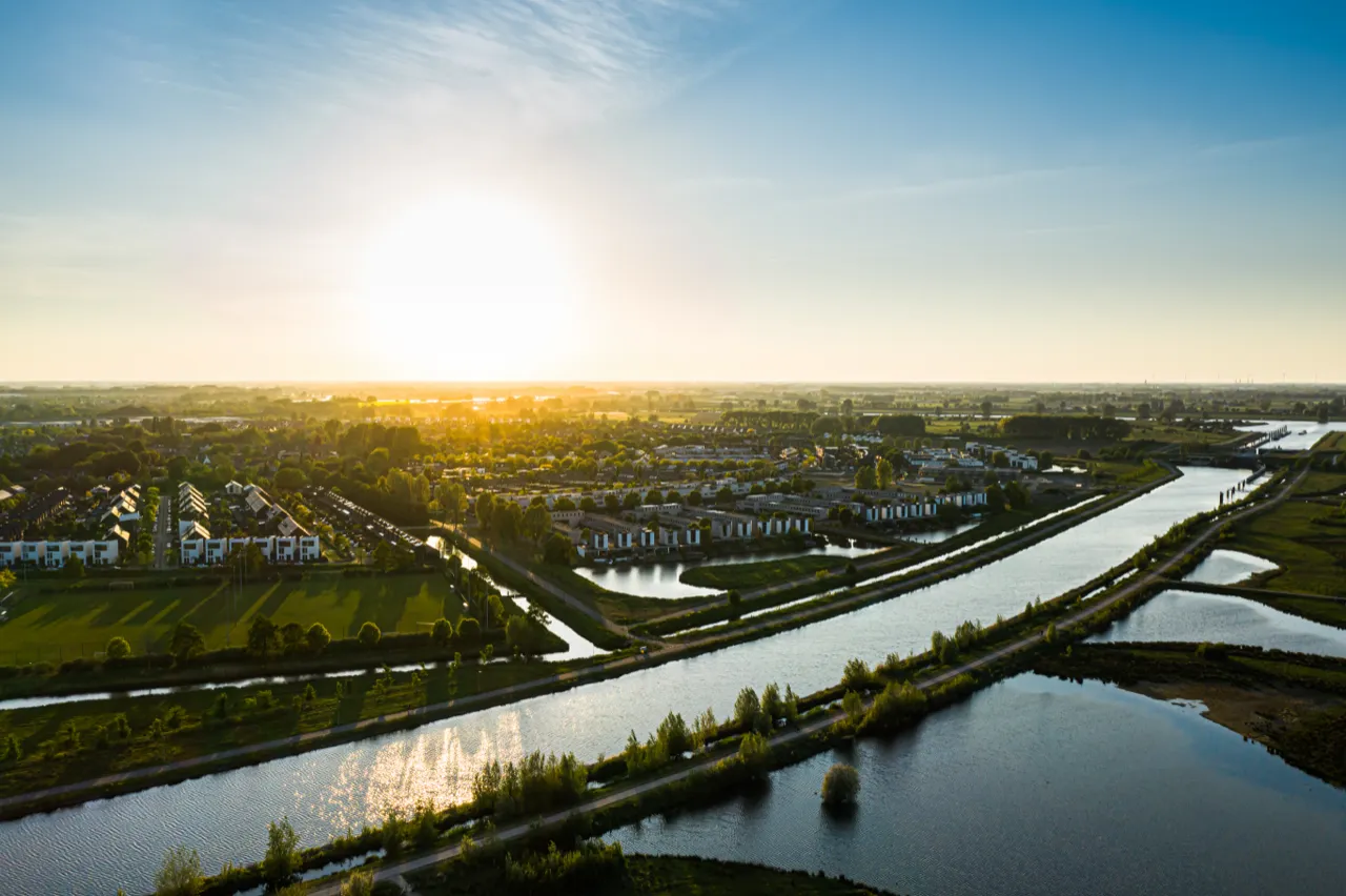 Zonsondergang boven een woonwijk aan het water, vanuit de lucht