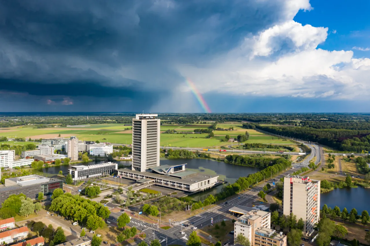 Regenboog boven de stad na een bui, vanuit de lucht