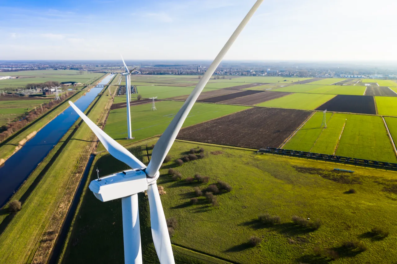 Windturbine van dichtbij boven de akkers, vanuit de lucht