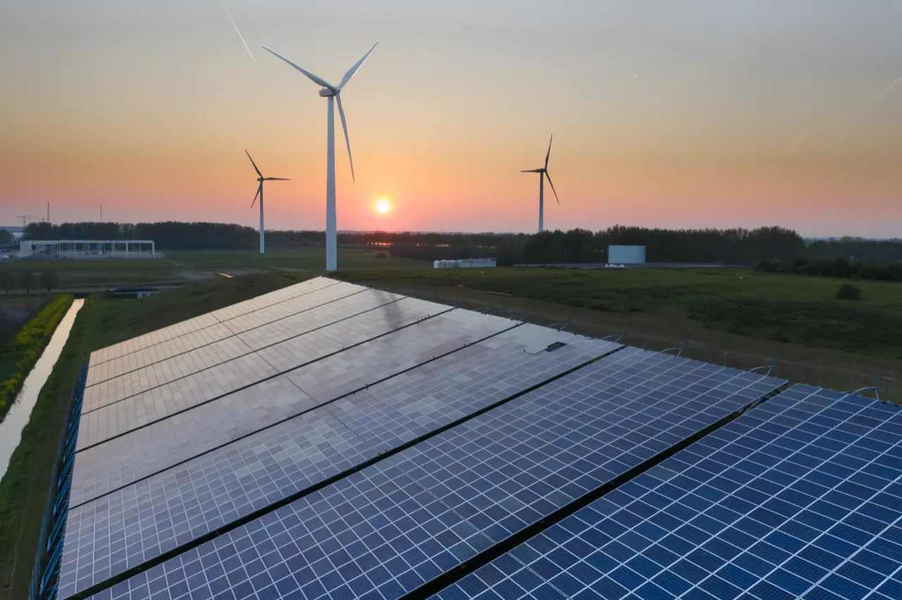 Zonnepark en windturbines bij zonsondergang, vanuit de lucht