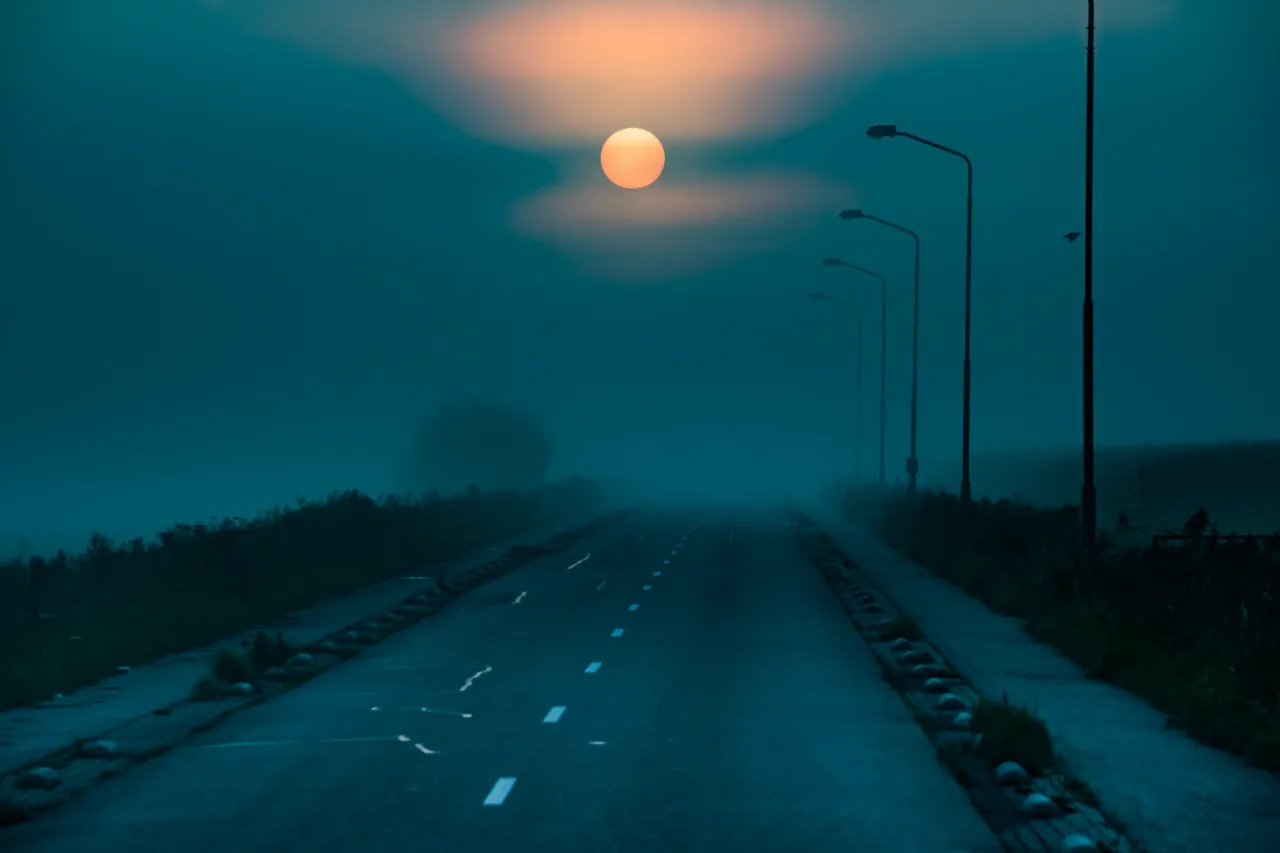 Maan boven een landweg in de schemering