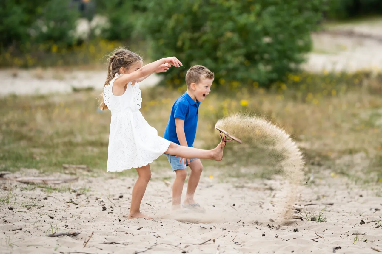 Twee kinderen die zand opgooien
