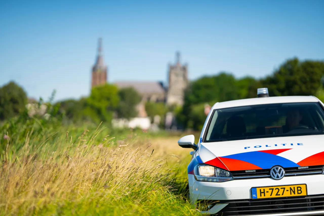 Politiewagen in het buitengebied, met een kerk aan de horizon