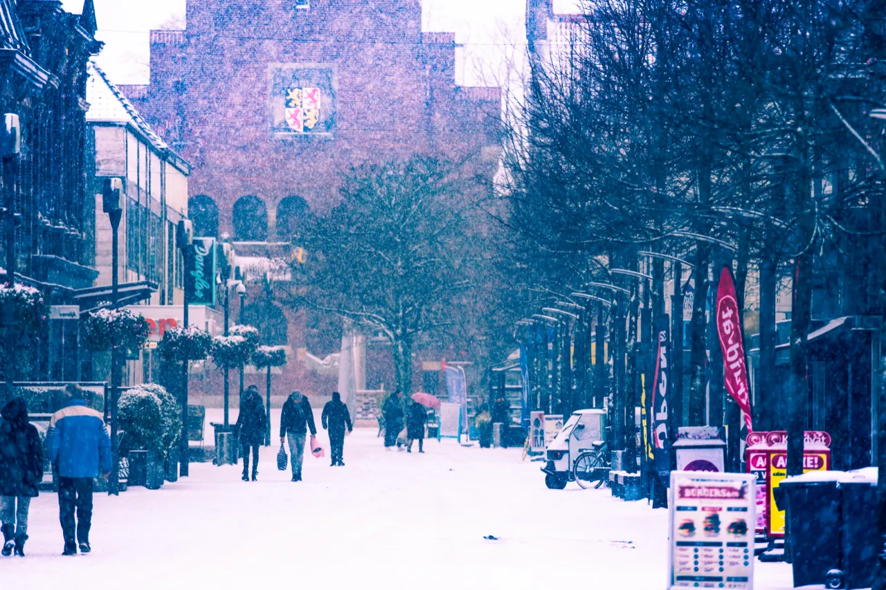 Besneeuwde winkelstraat langs een historisch gebouw