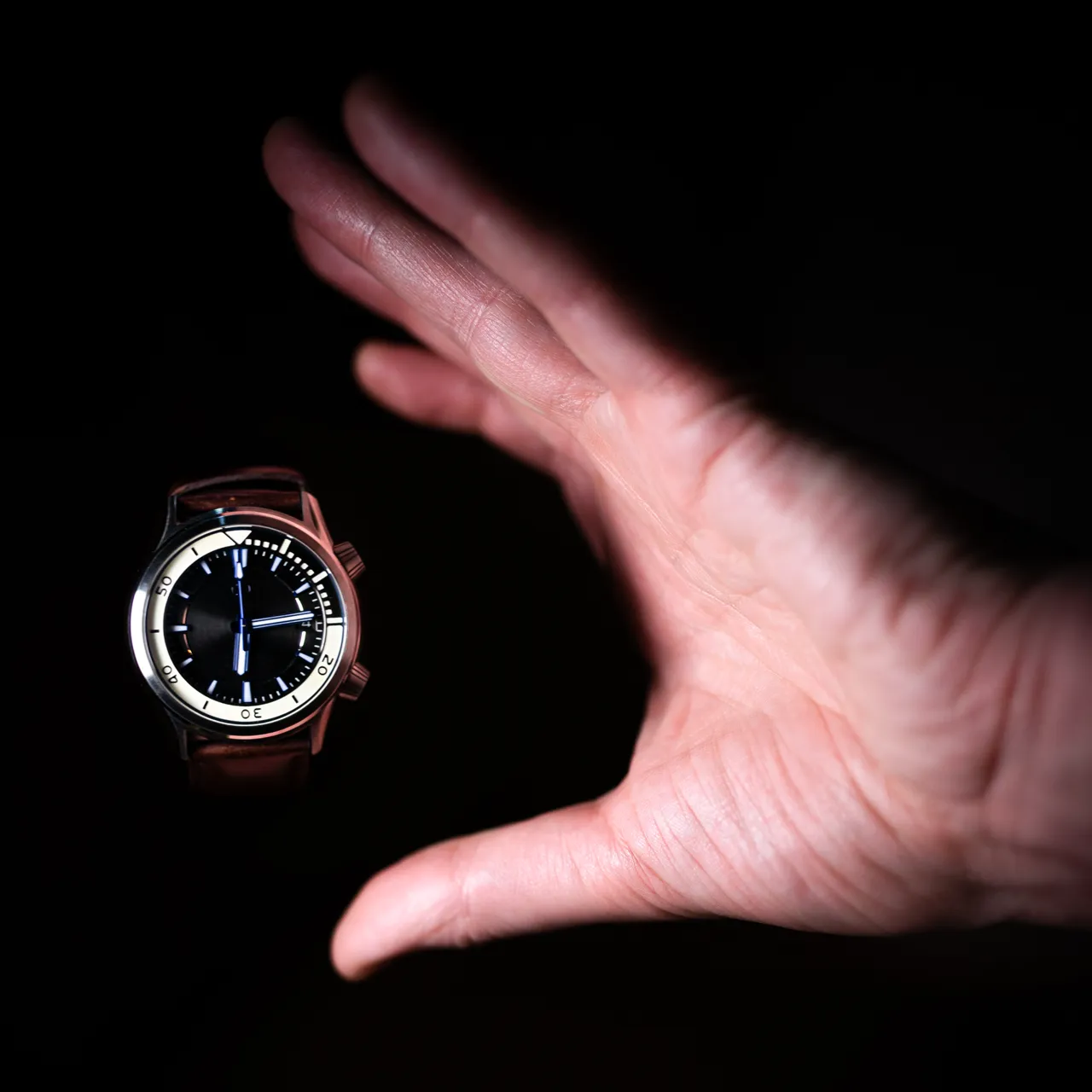 Horloge in de hand, tegen een donkere achtergrond