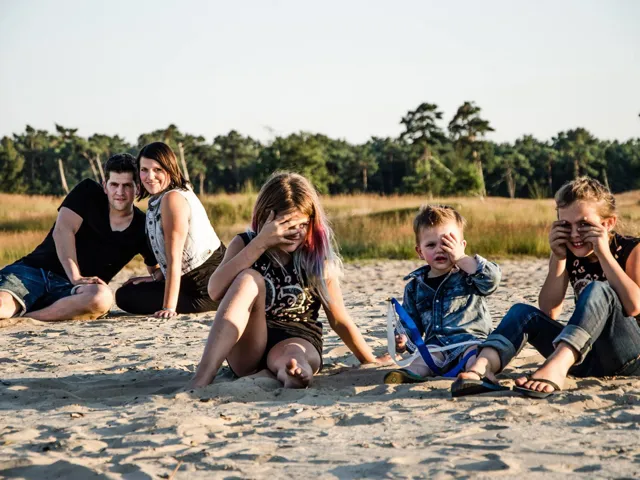 Gezin in het zand, de kinderen met hun handen voor hun ogen